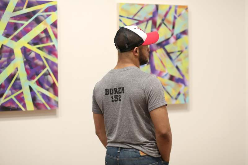 a man in a hat looking at a painting