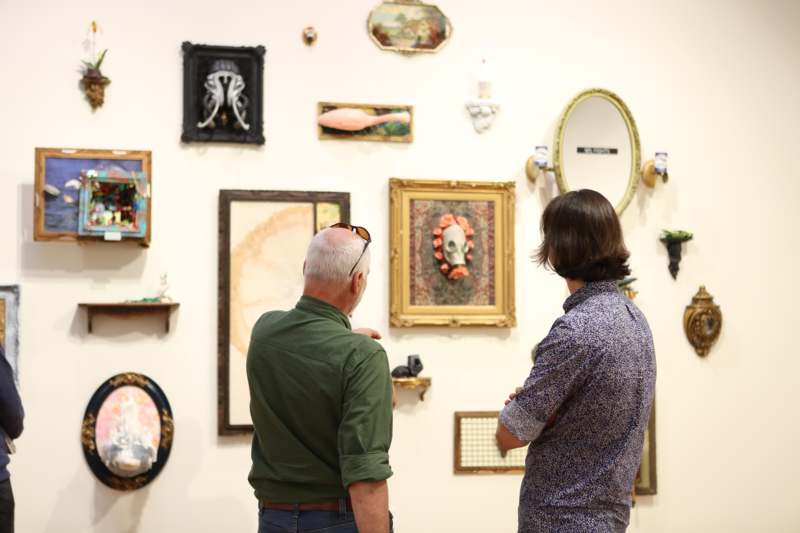 a man and woman looking at art on the wall