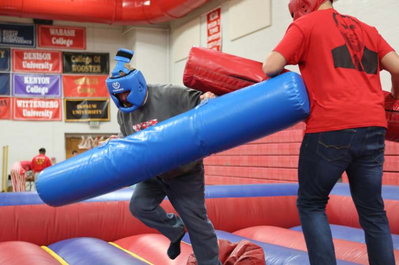 a man in a mask running on a large blue and red inflatable object
