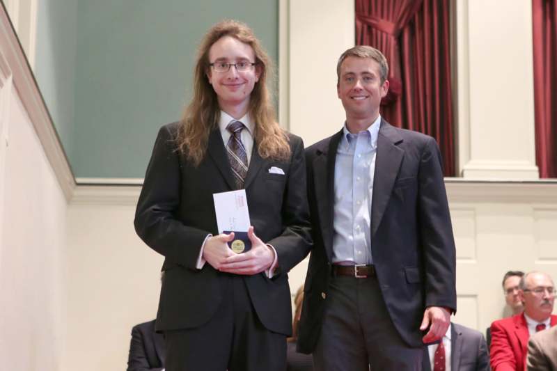 two men in suits holding a medal