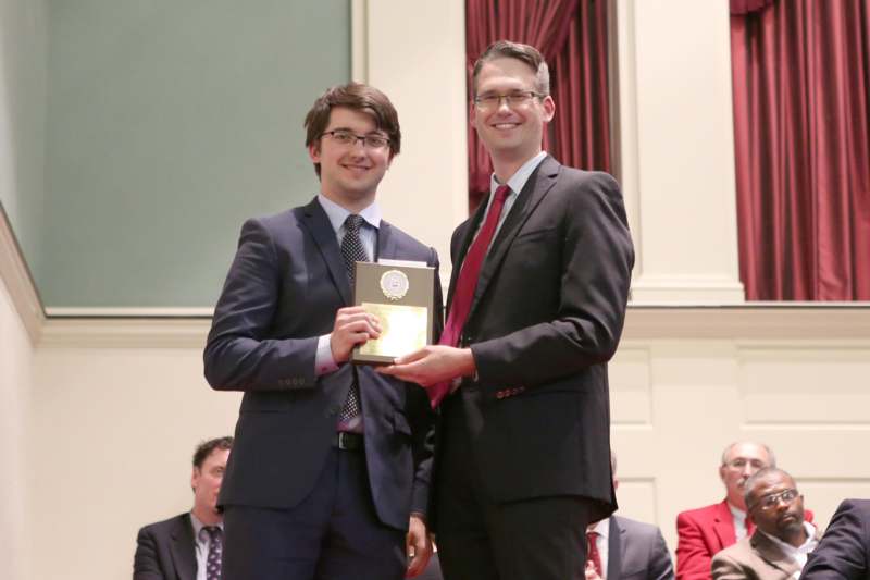 two men in suits holding a plaque