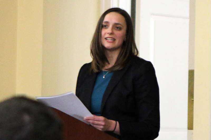 a woman standing at a podium holding a piece of paper