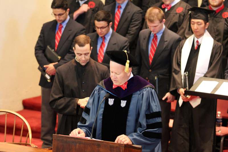 a man in a graduation gown and cap standing at a podium