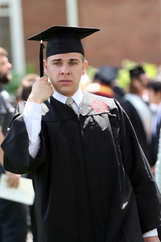 a man in a graduation gown holding a cap