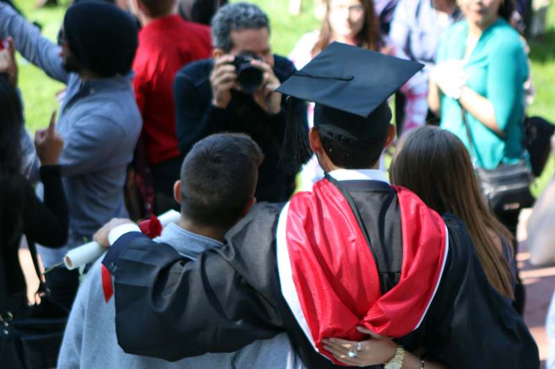 a man in a graduation cap and gown hugging a group of people