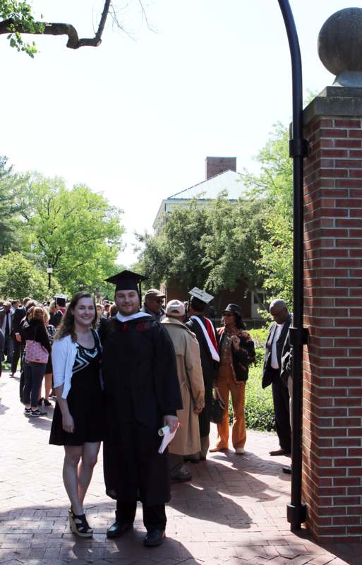 a man and woman in graduation gowns and cap standing in front of a brick wall