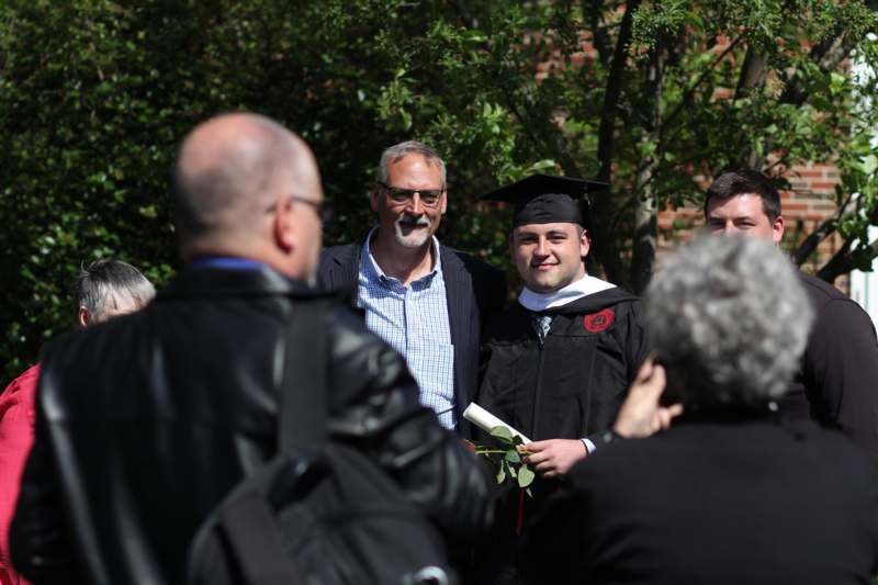 a man in a cap and gown standing in front of a group of people