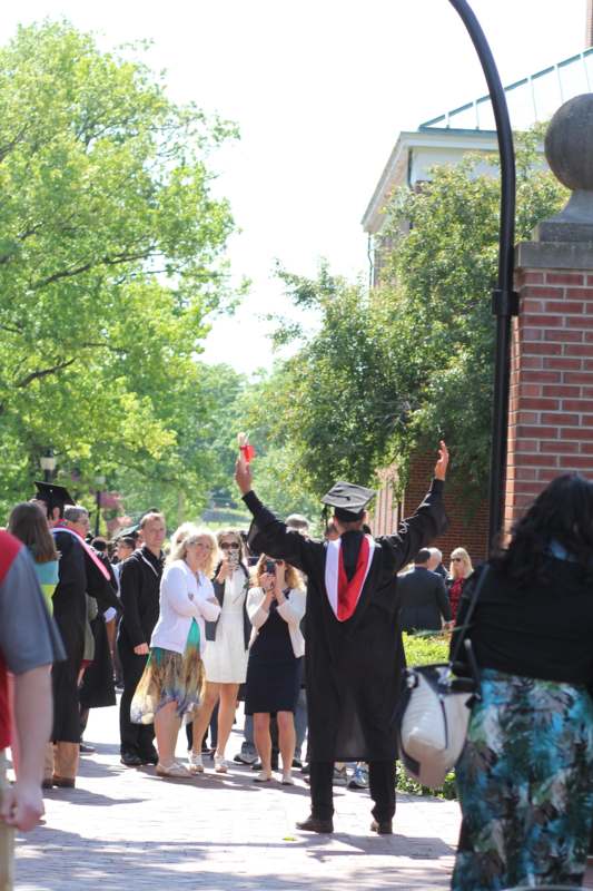 a man in a graduation cap raising his hand