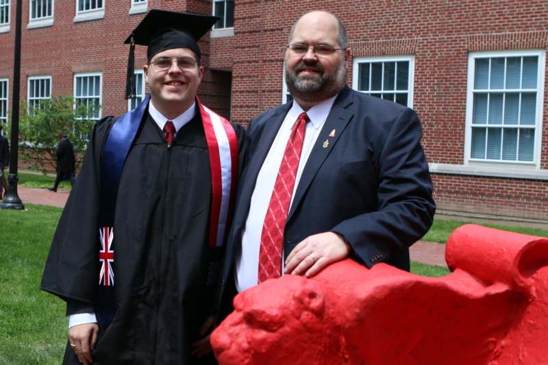 two men in suits and ties standing in front of a red lion statue