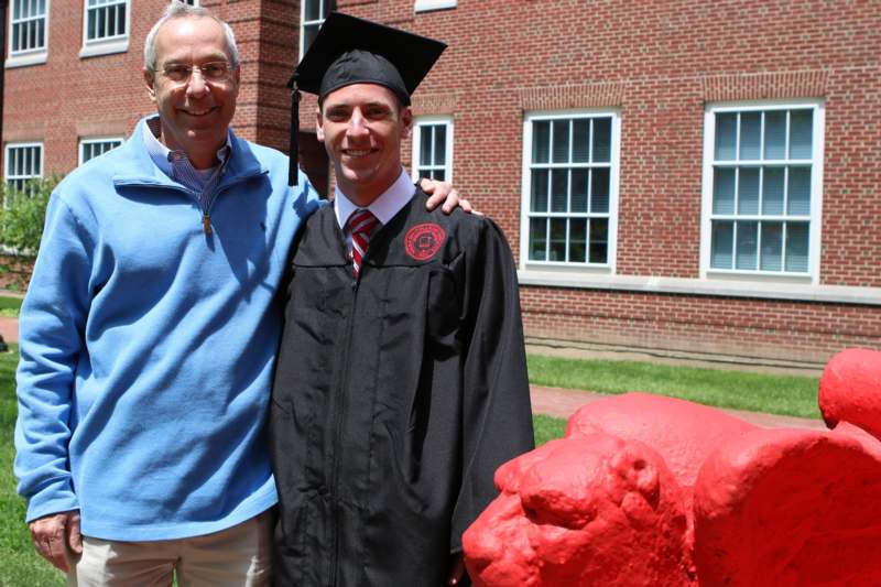 a man in a cap and gown standing next to a red statue of a bull