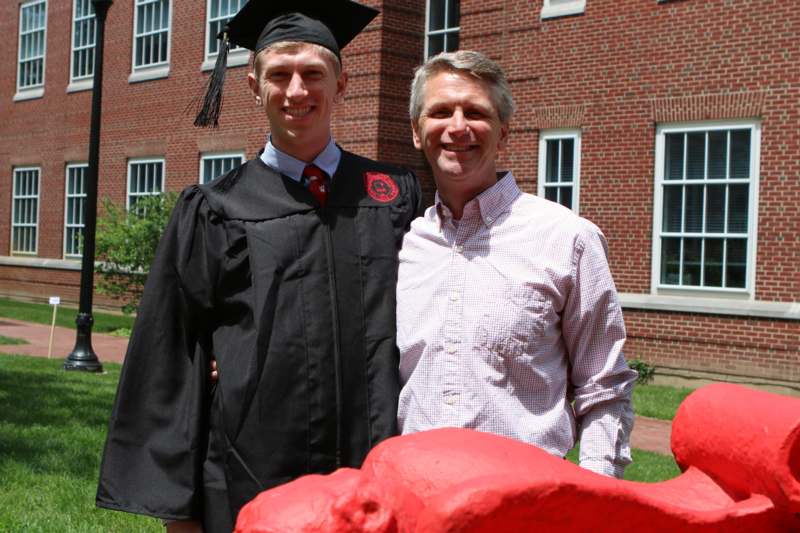 a man in a graduation cap and gown standing next to a man in a cap and gown