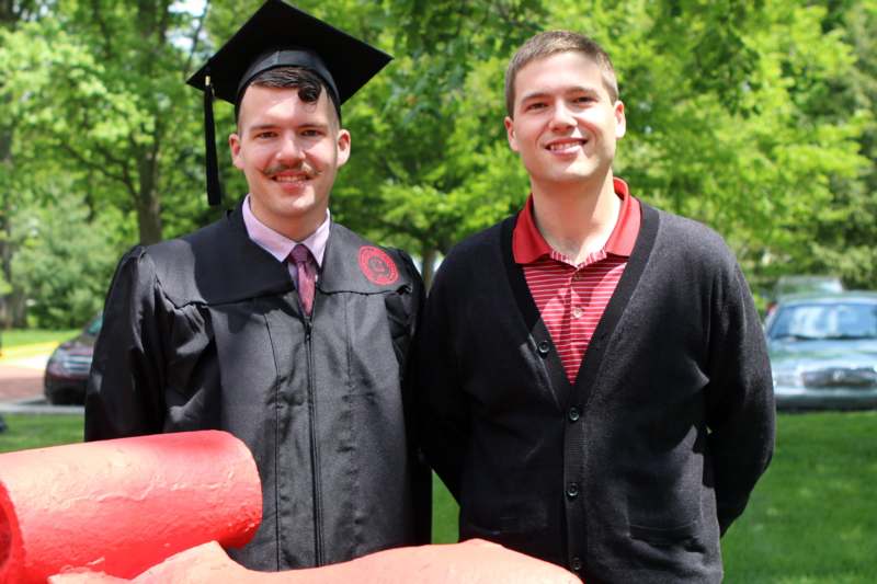 two men in graduation gowns and cap standing next to each other