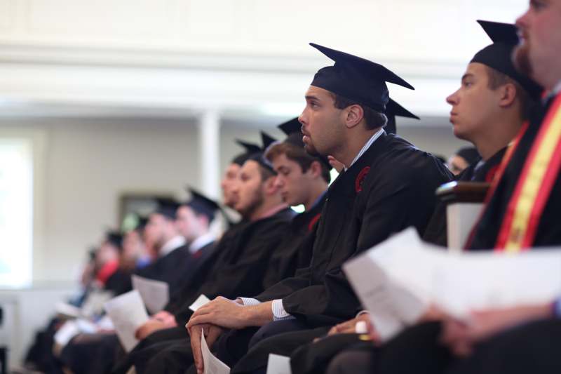 a group of people in graduation gowns and caps sitting in a row