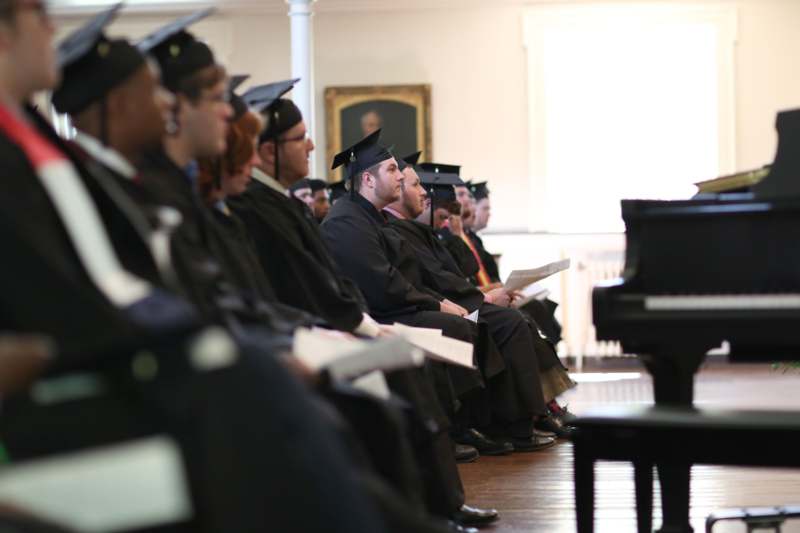 a group of people in graduation gowns and caps sitting on a stage