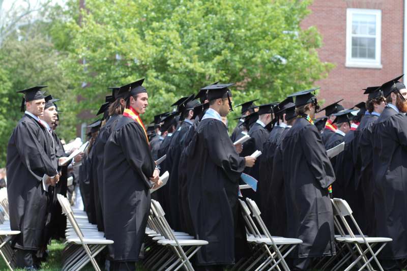 a group of people in graduation gowns and caps standing in chairs