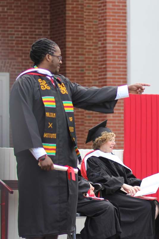 a man in a graduation gown pointing to a woman