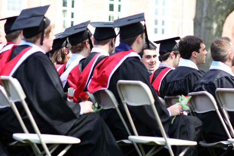a group of people in graduation gowns and caps sitting in chairs