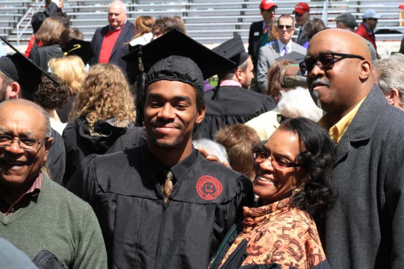 a man in a graduation gown and cap with a woman in a crowd
