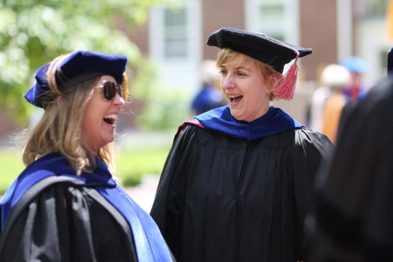 a woman in a graduation gown and cap laughing