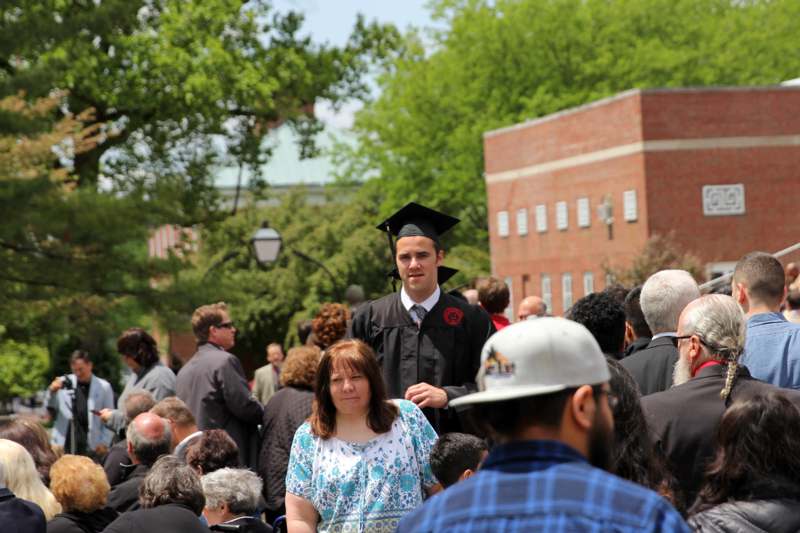 a man in a graduation cap standing in front of a crowd of people