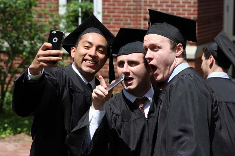 a group of men in graduation gowns and caps taking a selfie