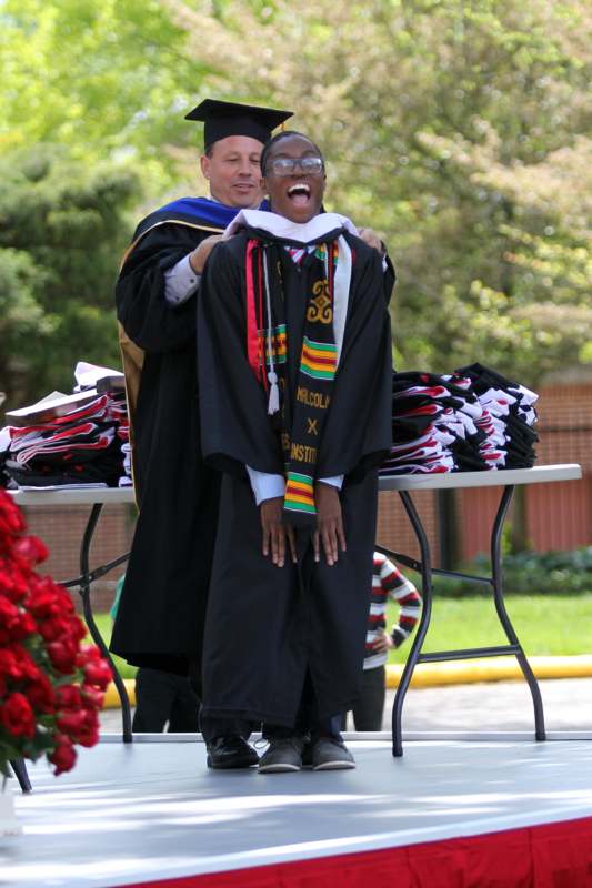 a man holding a woman's graduation gown