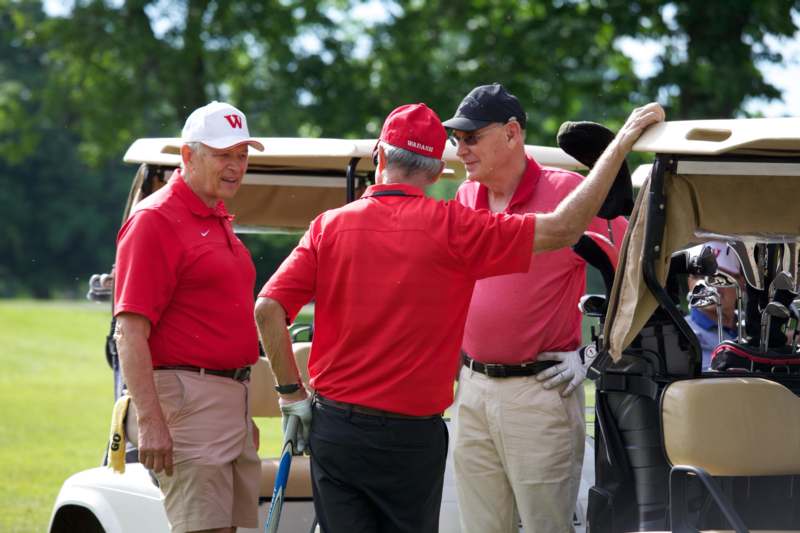 a group of men standing next to a golf cart