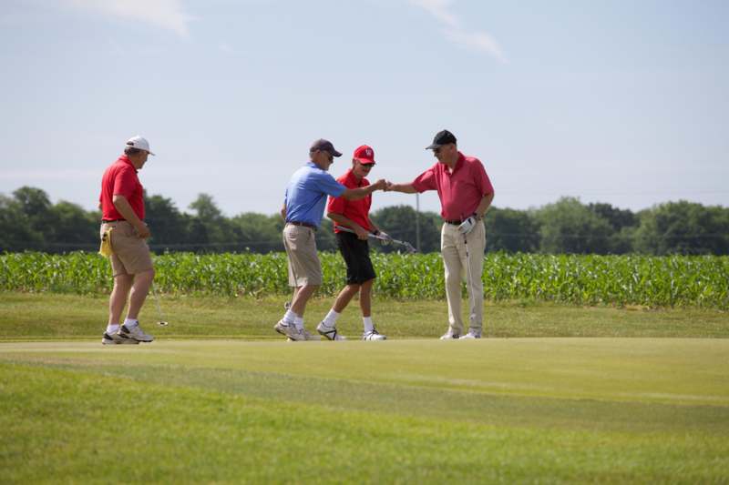 a group of men shaking hands on a golf course