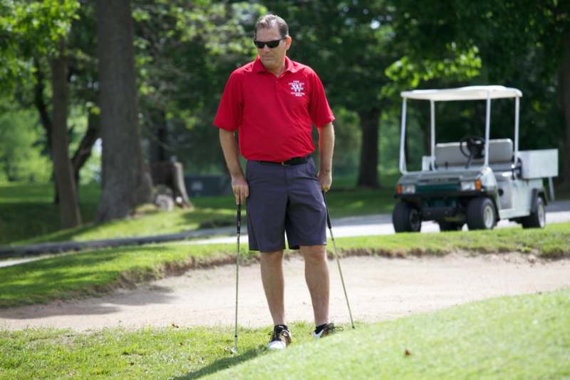 a man in a red shirt holding golf clubs