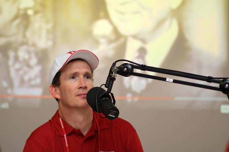 a man in a red shirt and white cap with a microphone