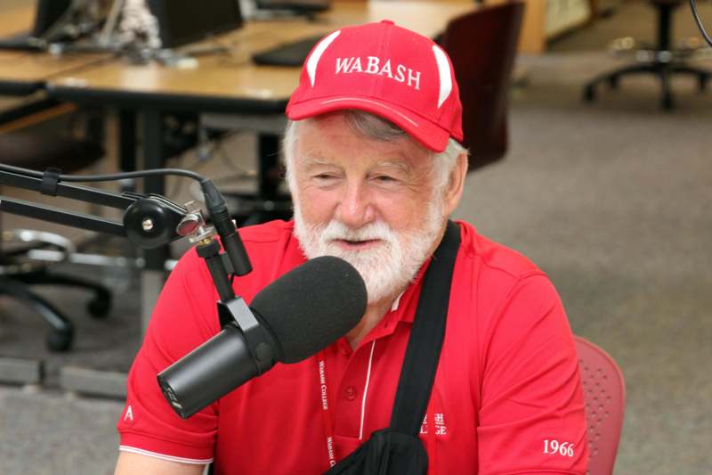 a man in a red shirt and cap speaking into a microphone