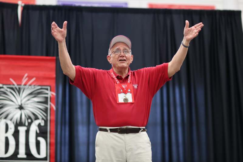 a man wearing a red shirt and white cap with his arms raised