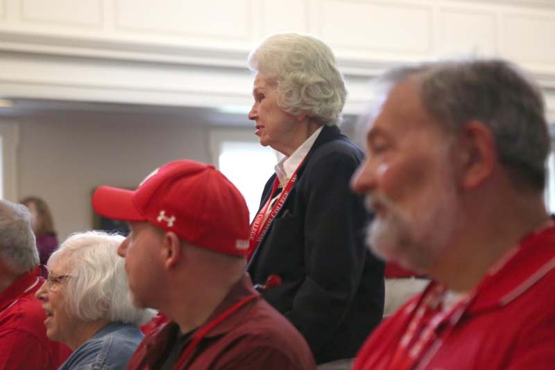 a woman in a red hat speaking to a group of people