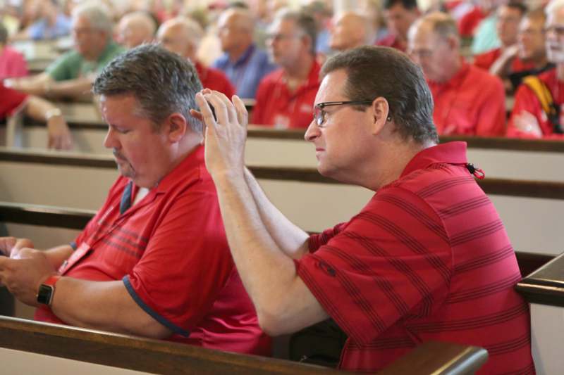 a group of men in red shirts sitting in a church