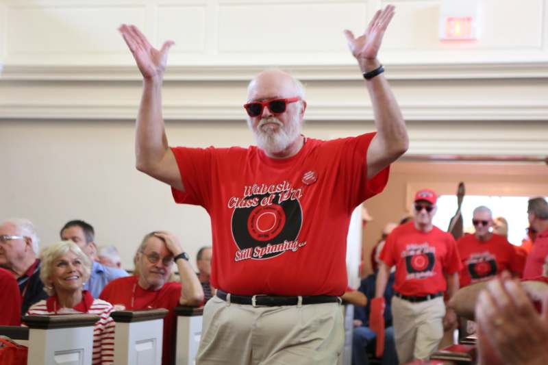 a man wearing red sunglasses and a red shirt with his hands up