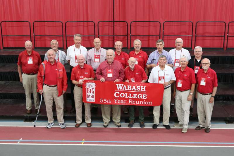 a group of men wearing matching outfits holding a red banner