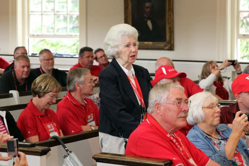 a woman standing in a room with people in red shirts
