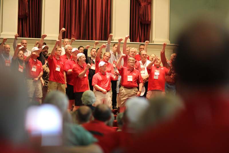 a group of people in red shirts raising their hands