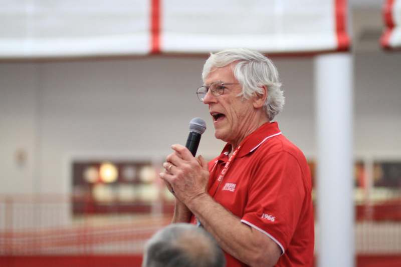 a man in a red shirt speaking into a microphone
