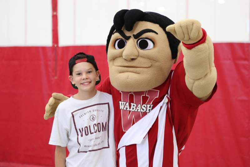 a boy standing next to a mascot