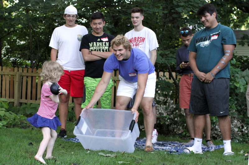 a group of people standing around a child holding a plastic container