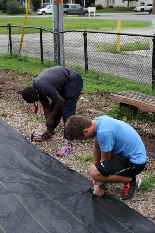 a couple of men tying shoes on a tarp