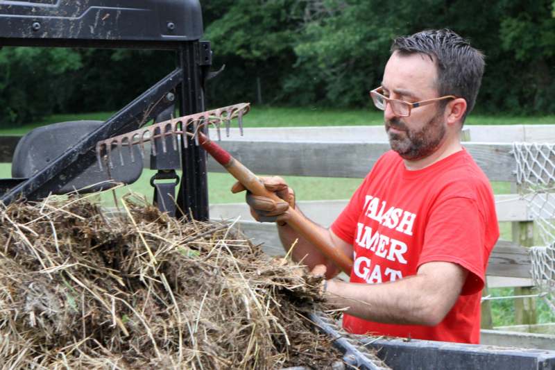 a man in a red shirt using a rake