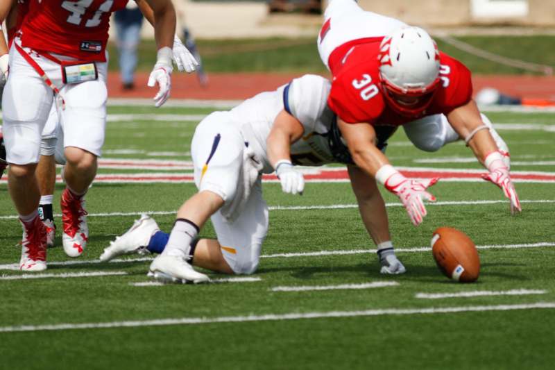 a football player falling to the ground while another player dives