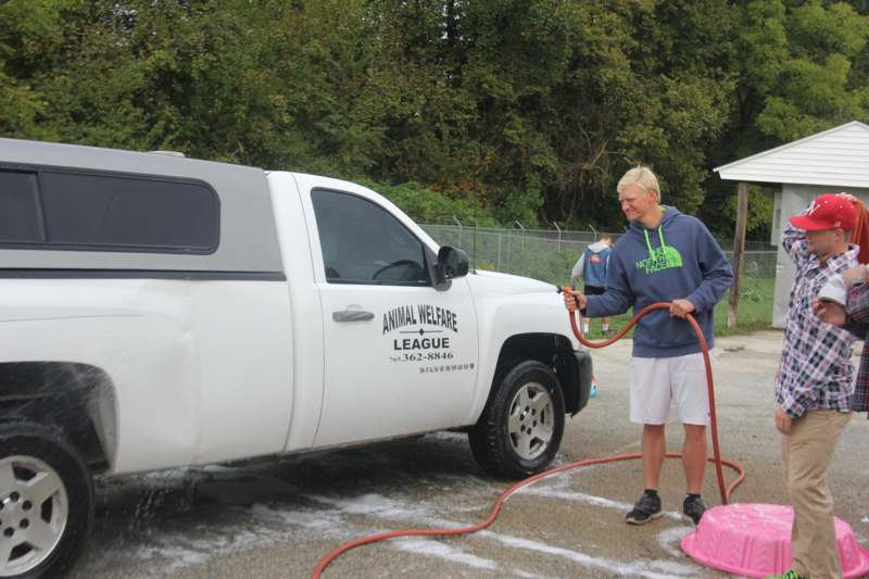 a man holding a hose to a truck
