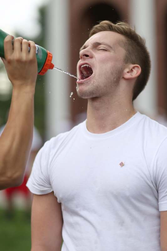 a man pouring water from a bottle into his mouth