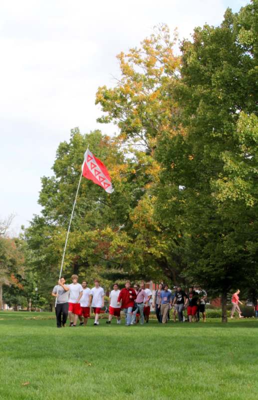 a group of people walking on a grass field with a flag
