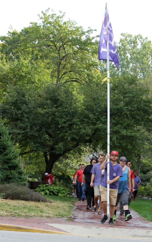 a group of people walking on a path with a flag pole