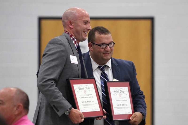 a couple of men holding certificates