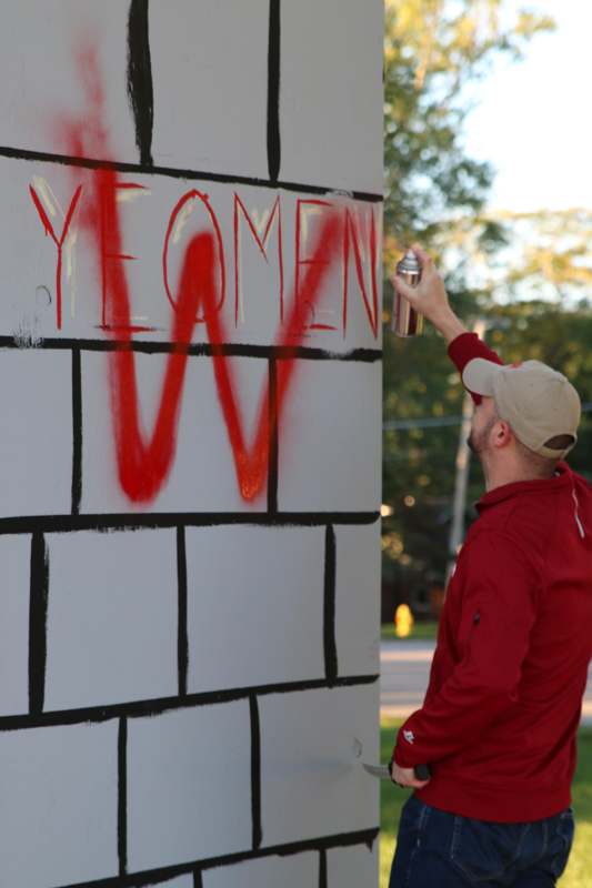 a man painting a wall with red spray paint